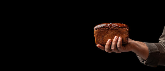 Wall Mural - kraft square rye loaf of bread in hand on black background, Baking bread at home, Long banner format. copy space for text