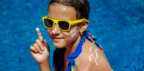 Poster - The child applies sunscreen. Selective focus.