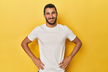 Young Hispanic man on yellow background confident keeping hands on hips.