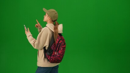 Portrait of person tourist isolated on chroma key green screen background. Close up shot young woman holding smartphone and looking at the departure board.