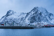 Winter scenic view of a Lofoten village with white and red typical houses and snowcapped mountains in the background
