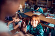 © Marko Geber - Young boy student high fiving teacher in classroom