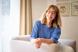 © sepy - Cropped shot of a middle-aged woman with blonde hair relaxing in an armchair at home