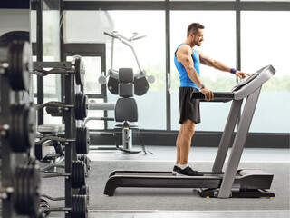 Wall Mural - Man turning on treadmill at the gym