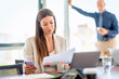 © gzorgz - Executive businesswoman sitting in a modern office and using laptop and smartphone