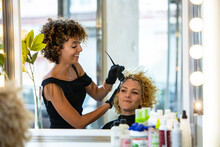 Hairstylist applying color to client's curly hair in a salon