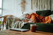 © ADDICTIVE STOCK - Young woman sleeping on comfortable sofa with cushion at home near laptop and mug