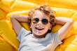 © ADDICTIVE STOCK - Joyful Child Relaxing on Yellow Float. Generative AI