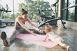 Parenthood and sport lifestyle. Young mother doing yoga with baby girl in gym.