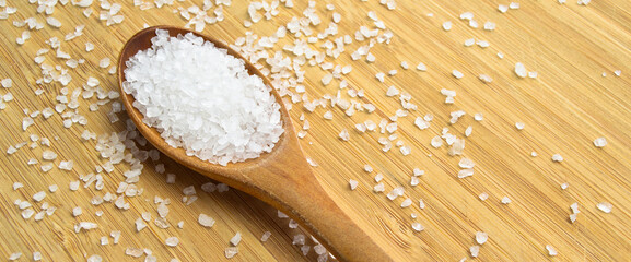 Wall Mural - Table rock salt used in dishes in a wooden spoon on a bamboo background