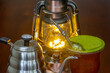 Traditional chimarrão prepared with yerba mate (Ilex paraguariesis) in a porongo gourd, next to a vintage lamp and barista-style gooseneck kettle