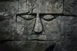 Ancient civilization's idol god face carved on the stone wall made of rock blocks.