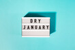 Text Dry January on the decorative lightbox isolated on blue background, mindful drinking