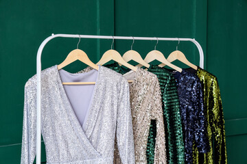 Rack with stylish female dresses near color wall, closeup