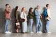 © Pixel-Shot - People waiting in line near grey brick wall