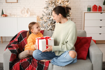 Poster - Young mother giving her little daughter Christmas gift at home