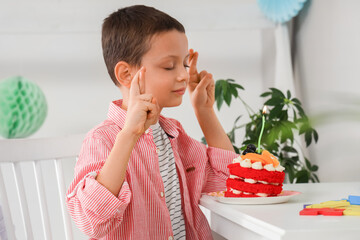 Wall Mural - Cute little boy with tasty cake making Birthday wish in room at home