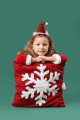 Wall Mural - Cute little girl in Santa Claus costume with beautiful Christmas cushion on color background