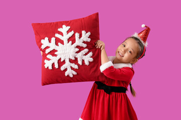 Wall Mural - Cute little girl in Santa Claus costume with red Christmas pillow on color background