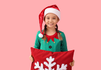 Wall Mural - Cute little girl in elf costume with Christmas pillow on pink background