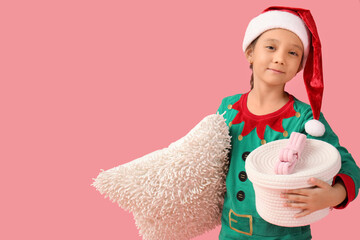 Wall Mural - Cute little girl in elf costume with basket and cushion on pink background