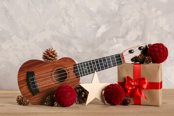 Wall Mural - Composition with ukulele, Christmas gift and decorations on wooden table against grunge background