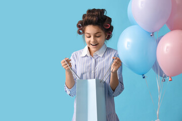 Poster - Little girl with hair curlers, shopping bag and balloons on blue background