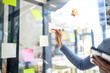 © David - Happy asian businesswoman planning new project with sticky note in a creative writing on blank office glass