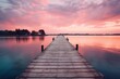  a wooden dock extending into a body of water with a pink sky in the background and clouds in the sky.