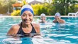 Smiling senior American woman in swim cap enjoys group swimming in sunny outdoor pool 