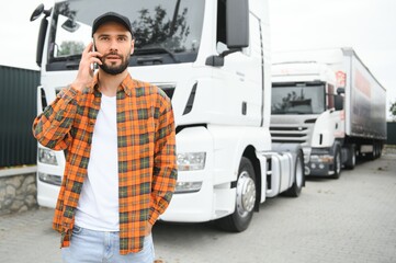 Man trucker talking on the phone by his white truck