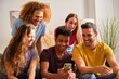© Ladanifer - Group of cheerful young multiethnic friends watching social network funny content on a smartphone screen.