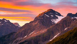 Fototapeta Fototapeta z niebem - Kolorowe niebo w odcieniach pomarańczy i różu, zachodzące słońce odbijające się od szczytów gór