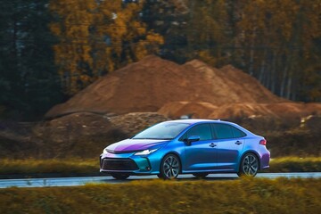 Modern Japanese sedan covered with protective colorful film. Car covered with adhesive chameleon foil. Blue-purple sport car wraped vinyl film with a magenta tone.