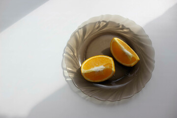 Two slices of orange on a plate on a white background, shadow