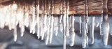 Fototapeta Panele - A wooden house covered in ice and icicles hanging from the roof Wooden tower covered with ice in cold winter. Copy space image. Place for adding text