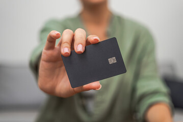 Lady hand shows dark credit card with chip for contactless payment close up. online shopping mobile payment banking