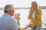 Fototapeta  - Senior Gentleman Making Proposal To Happy Excited Lady Outdoors