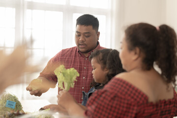 Asian family cooking together at kitchen. The chubby father and mother with girl feel happy in our morning breakfast in a weekend. cooking salad and vegetables.