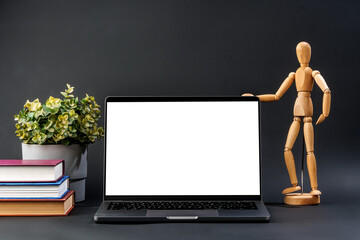 Canvas Print - Open laptop with wooden mannequin on table against black background