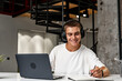 © fotofabrika - Young man wearing headphones while studying with laptop