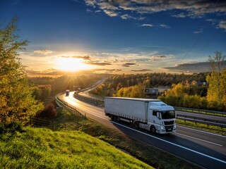 Wall Mural - white trucks driving on the highway winding through forested landscape in autumn colors at sunset