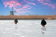 Ice sledging on a cold winterday at the windmill in the Netherlands at sunset