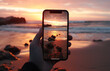 © goami - closeup shot of person holding mobile phone in hand and taking photo of beautiful sunset over sea, nature photography with smartphone camera