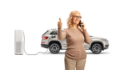 Woman using a smartphone and standing in front of a SUV at electric charging point