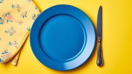 Wall Mural - Cutlery. Blue plate on a yellow table.