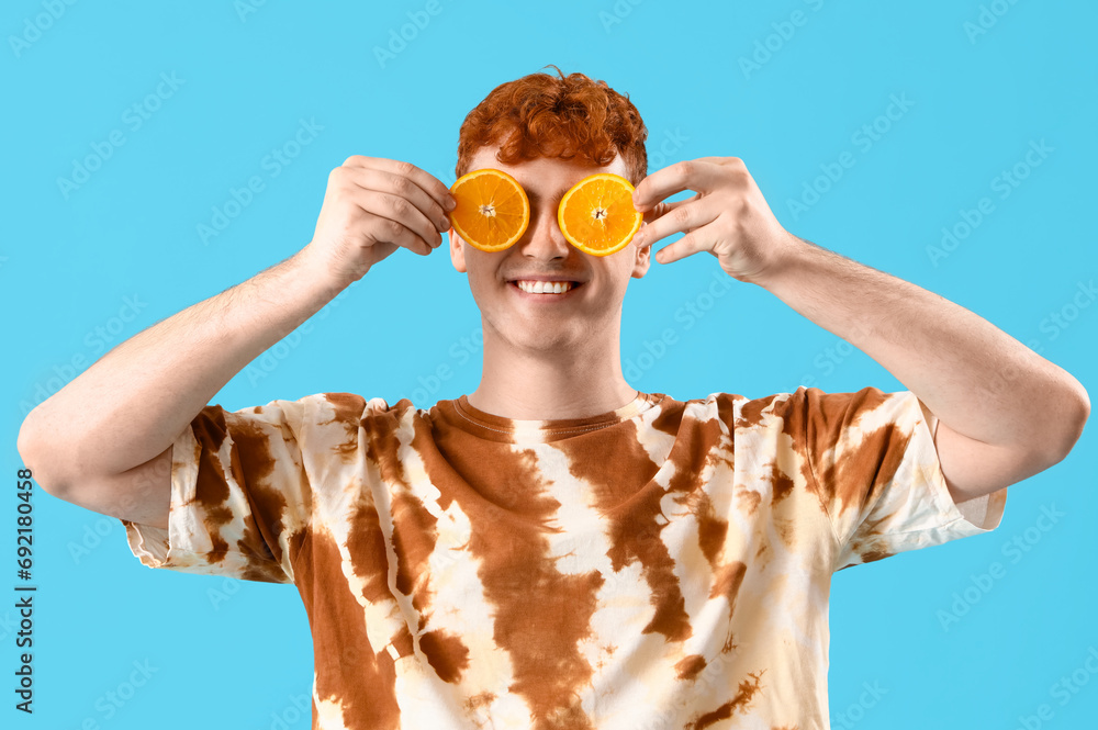 Young man with orange slices on blue background