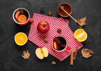 Wall Mural - Cups of hot mulled wine with apple and orange on black background