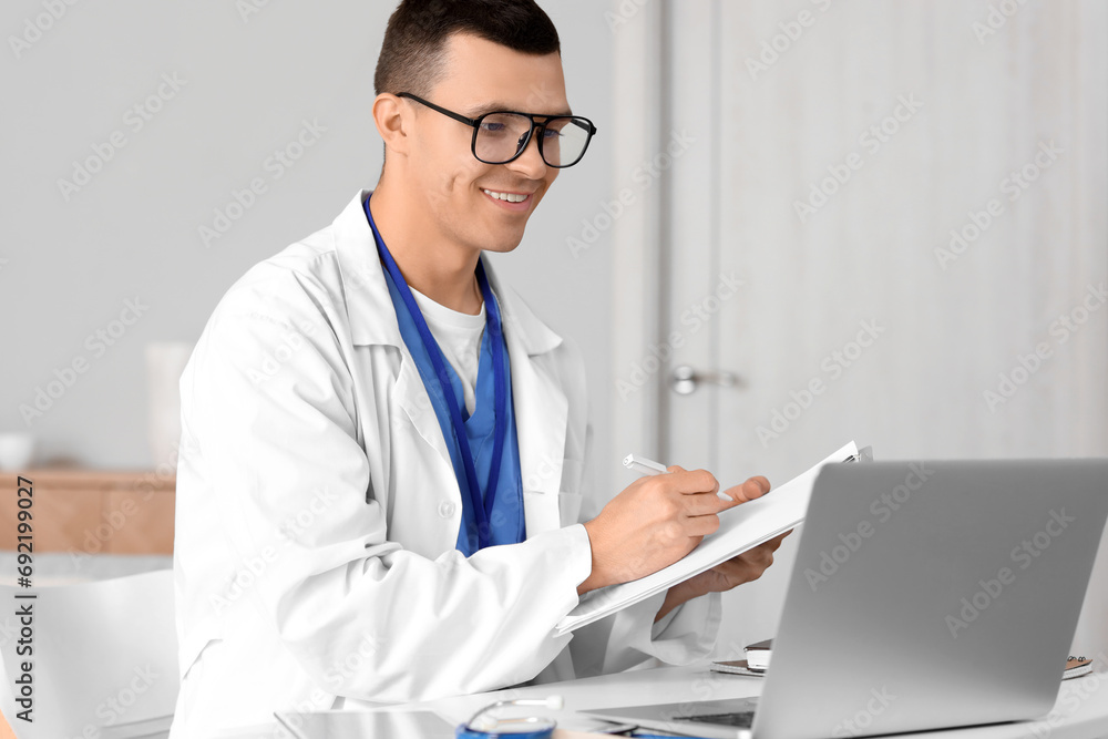 Young doctor video chatting with patient on laptop at home