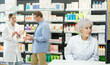 © JackF - Attentive old female pharmacist looking at display of computer in chemist's shop with large assortment